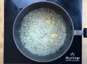 Pan of bubbling butter on stovetop close-up, perfect for cooking or baking recipes.
